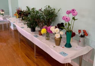 A well displayed table showing Garden Show entries for dahlias, shrubs and other vased blooms