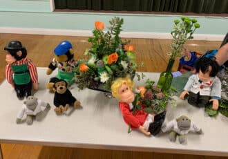 A selection of flower arrangements, all including "PG Tips" monkeys. One monkey is holding a bunch of orange roses and foliage.